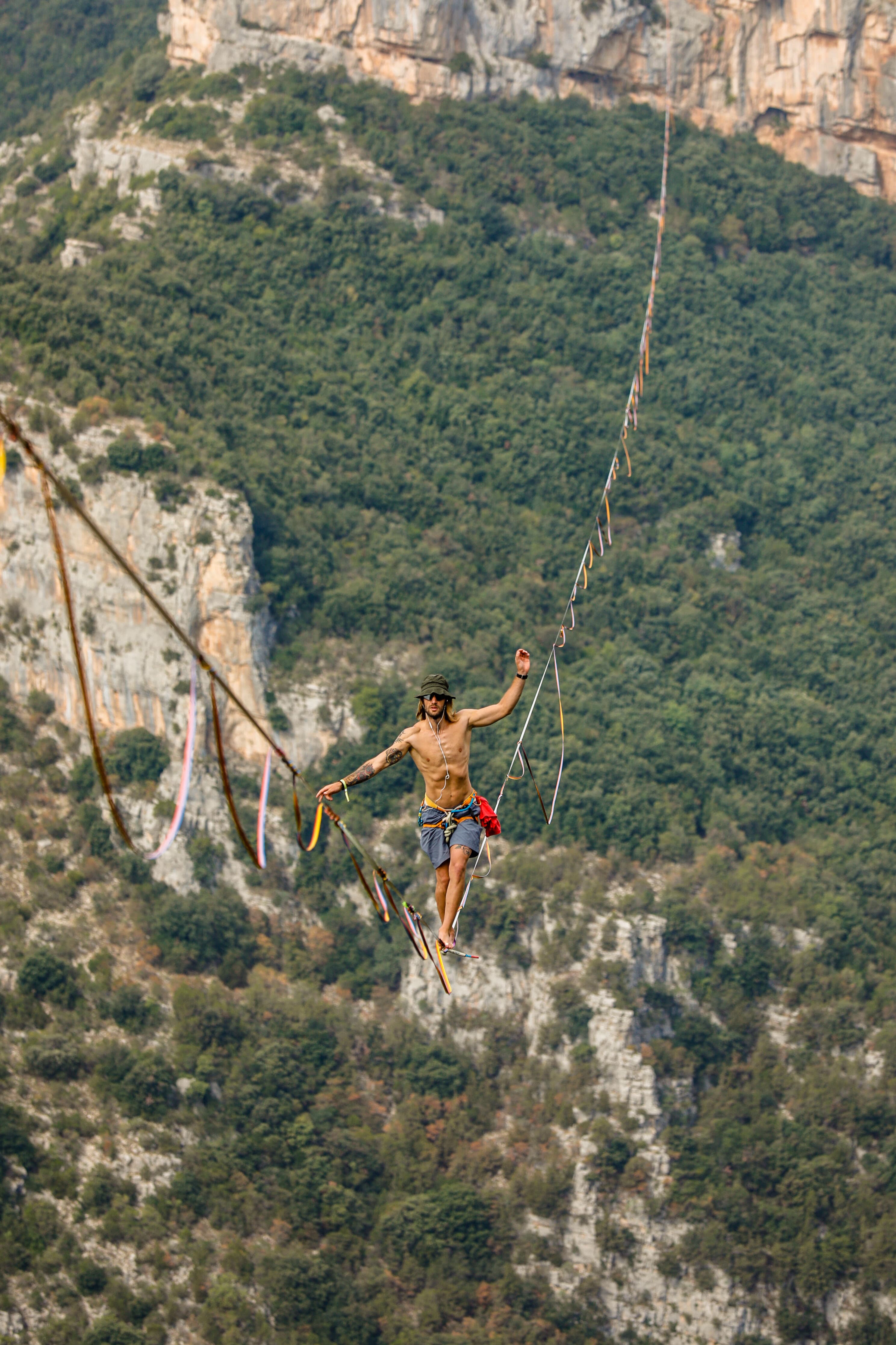Highline tesa sopra una gola boscosa, con una persona in equilibrio sulla linea
