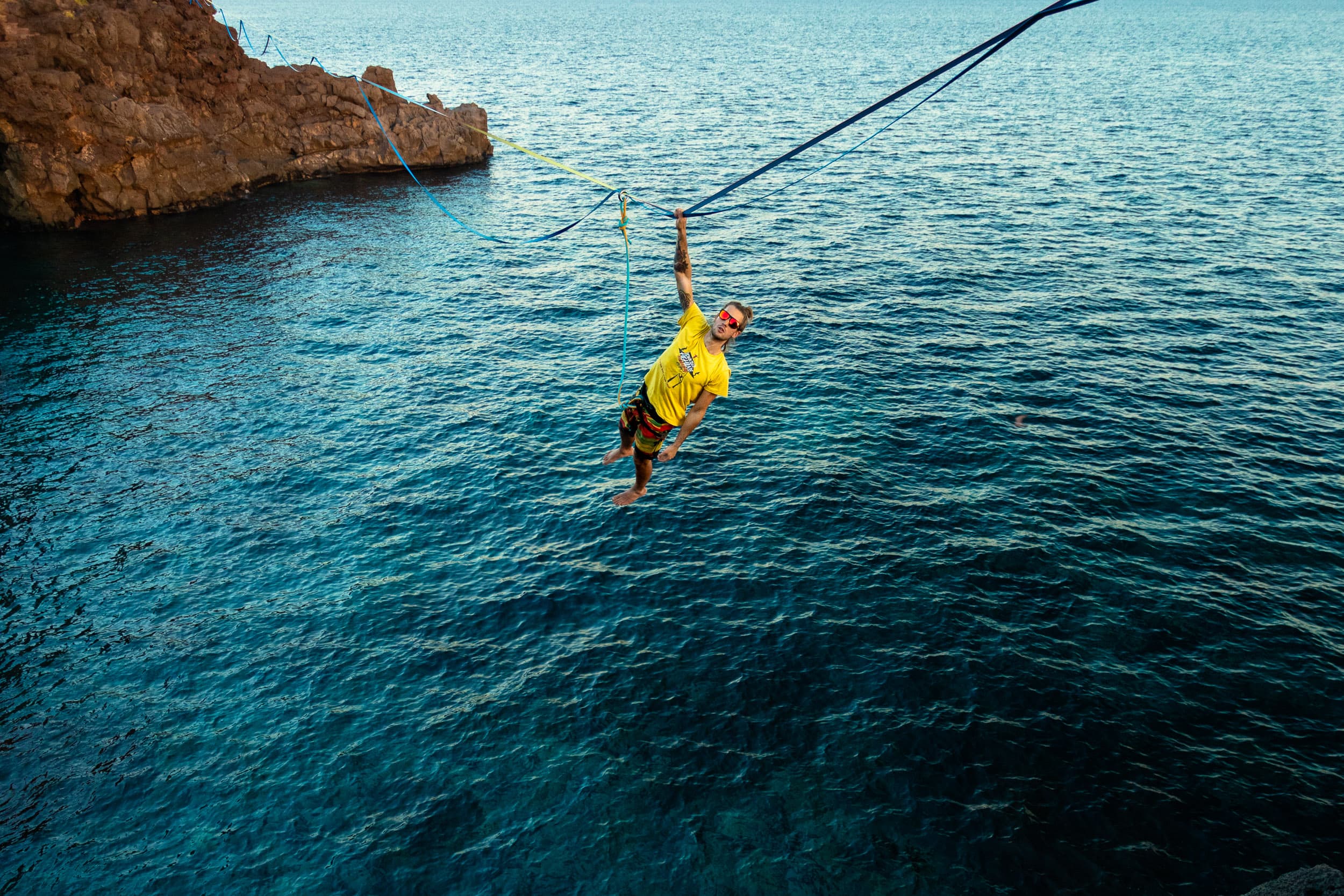Alessandro su una highline sopra il mare turchese tra due scogliere
