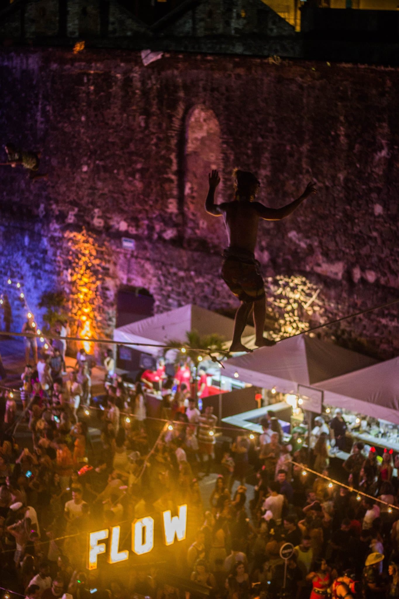 Alessandro in una performance notturna su una linea sospesa sopra il pubblico di un festival